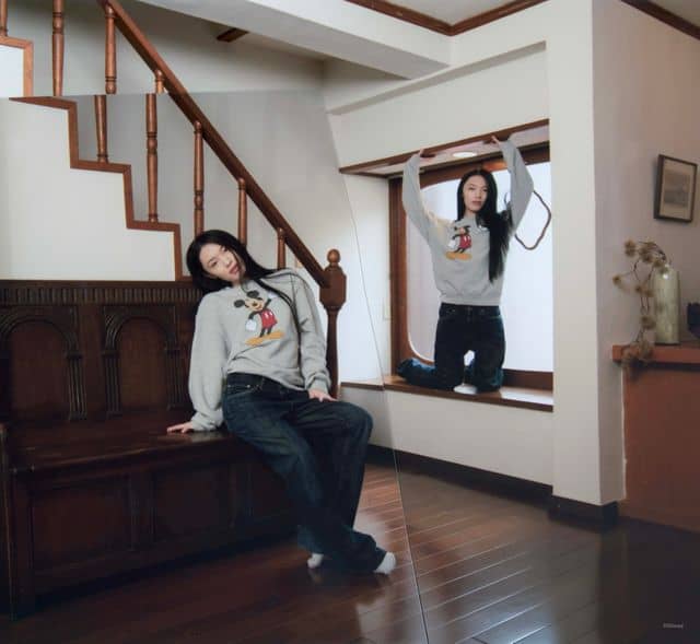 Young woman wearing Disney Mickey Mouse sweatshirt indoors.