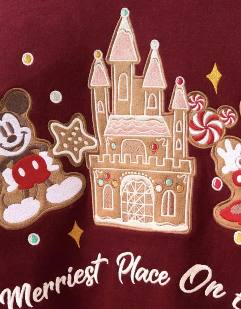 Colorful embroidered Disney castle with holiday embellishments on red fabric.
