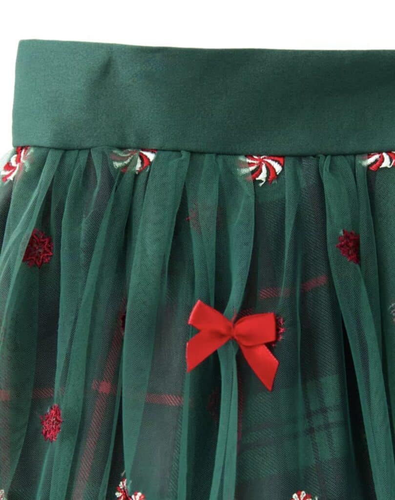 Green holiday skirt with candy cane embroidery and red bow detail.