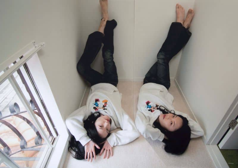 Girls lying on floor with Disney themed sweatshirts, relaxed indoor fashion, playful Disney style, cozy home outfit inspiration.