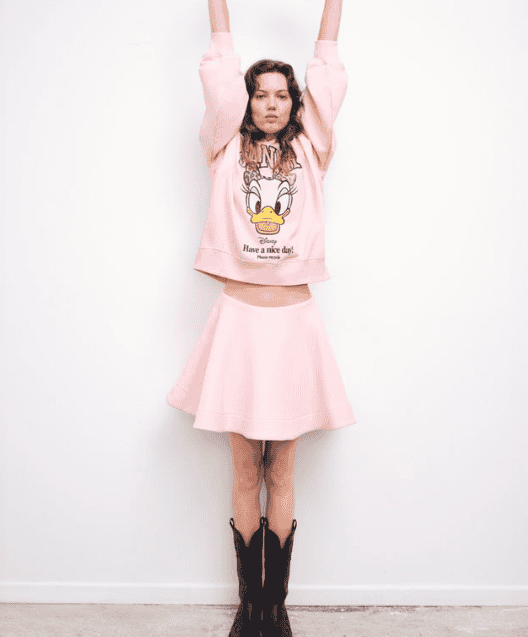 Vibrant pink Disney sweatshirt with Donald Duck graphic and trendy skirt, perfect for Disney fashion lovers.