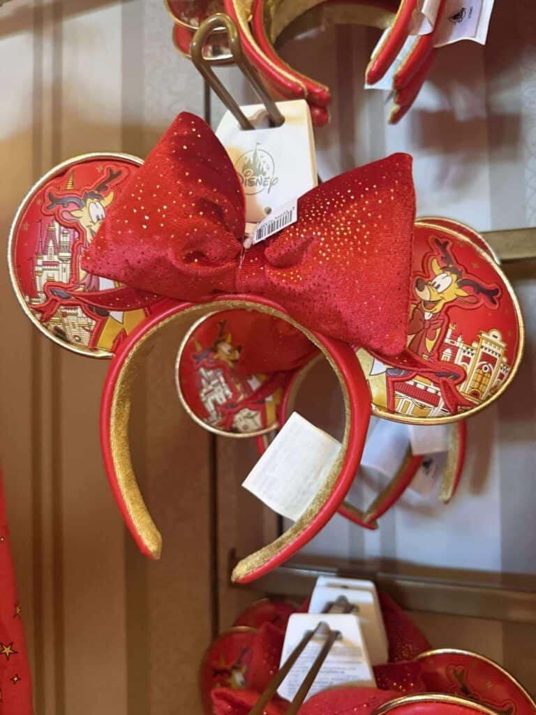 Red Minnie Mouse ears headband with a glittery red bow and Disney castle design, perfect for Disney fashion enthusiasts.