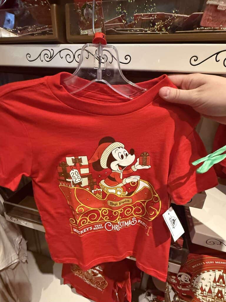 Mickey Mouse Christmas T-shirt featuring festive design with presents and sleigh, in red color, perfect for Disney holiday celebrations.