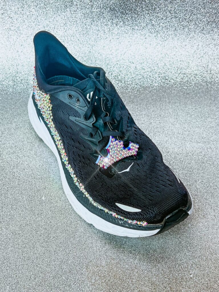 Stylish black athletic shoes adorned with multicolored rhinestones and a thick white sole.