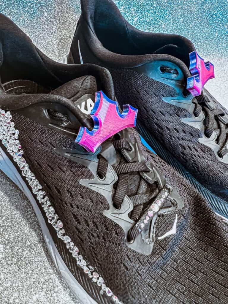 Athletic black sneakers featuring pink star-shaped embellishments and rhinestones, perfect for Disney fashion lovers.