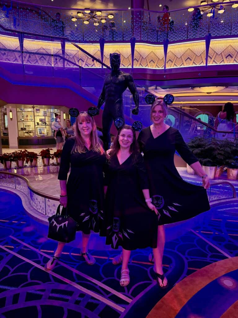 High-resolution image of three women wearing Black Panther-inspired dresses at Disney event.