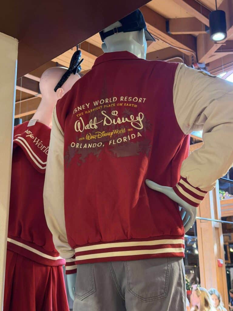 Mannequin wearing a Disney World Disney Resort red and cream varsity jacket at Disney merchandise store.