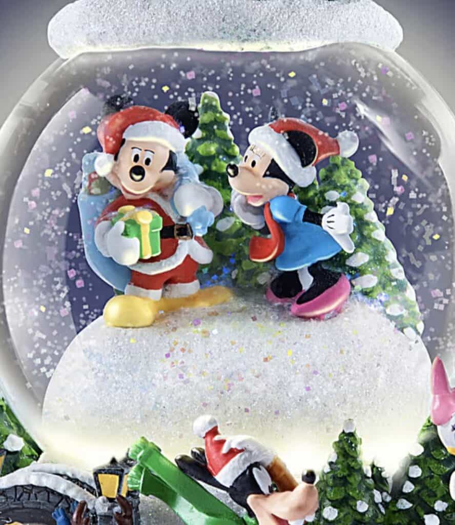 Colorful Disney holiday snow globe with Mickey and Minnie characters and festive winter scene.