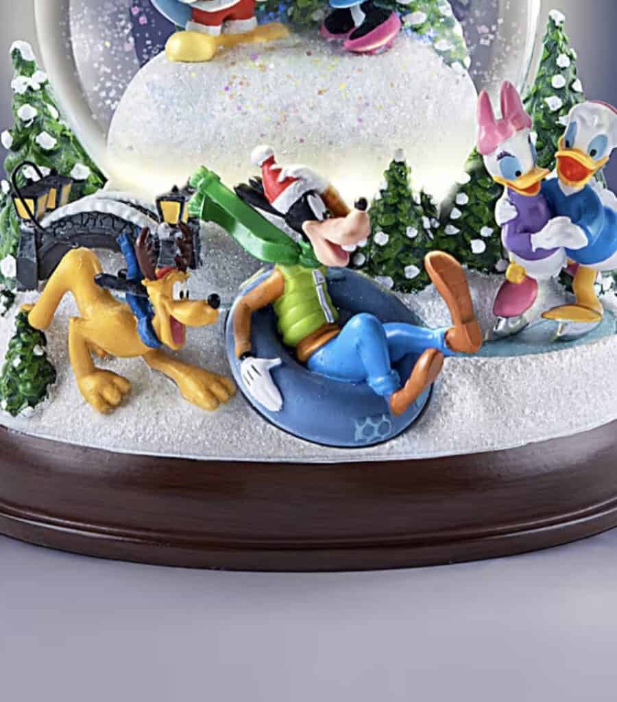 Colorful Disney snow scene with Mickey, Minnie, Pluto, and Donald in winter gear. Festive holiday decorations.