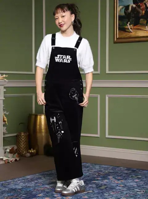 Young woman wearing black Star Wars overalls with white graphic prints, stylish and trendy Disney-inspired outfit.