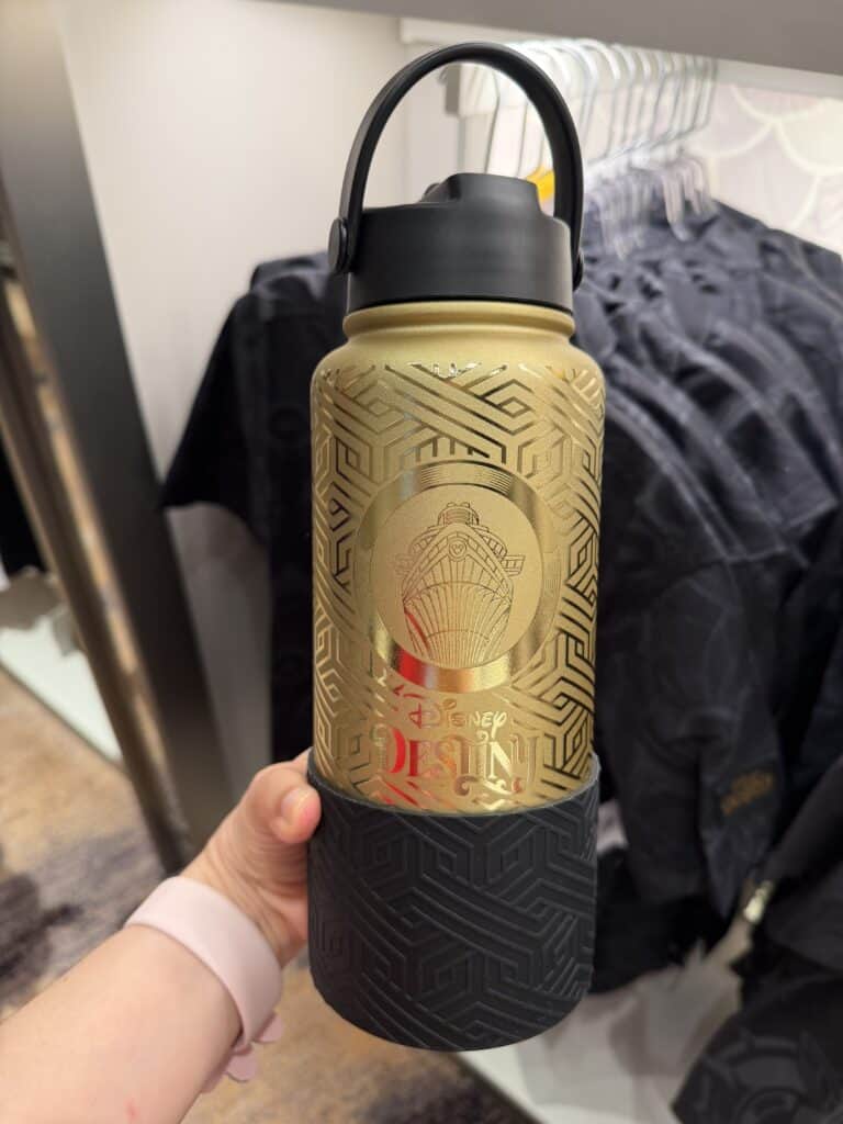 A gold Disney-themed water bottle featuring a ship design and "Disney Desiny" logo, with black grip and lid, perfect for Disney fans.