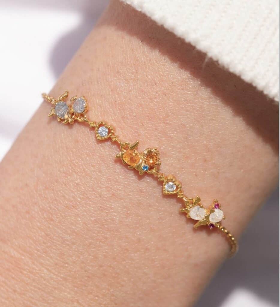 Delicate gold bracelet with colorful, Disney-themed gemstones for elegant style.