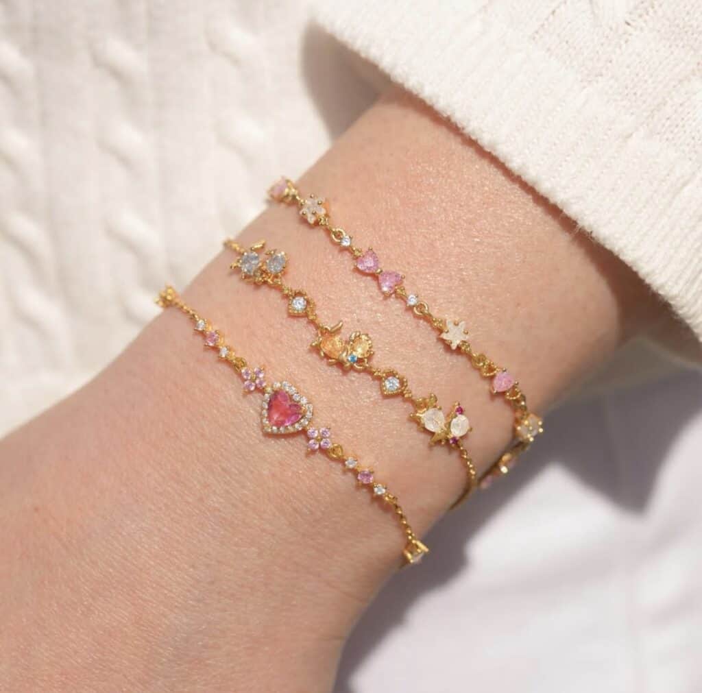 Disney themed charm bracelets featuring hearts, stars, and pastel-colored stones in gold settings.