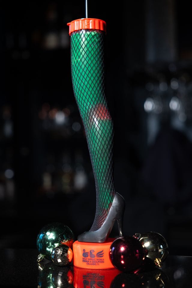 A whimsical figure of a woman wearing fishnet stockings and high heels, surrounded by colorful Christmas ornaments.
