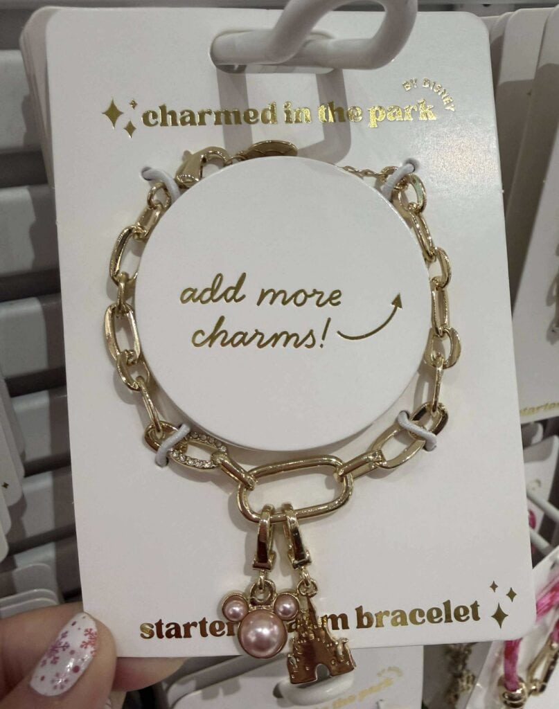 Charm bracelet featuring Disney-inspired charms, gold links, pink pearls, and playful design, ideal for Disney fans and charm jewelry collectors.