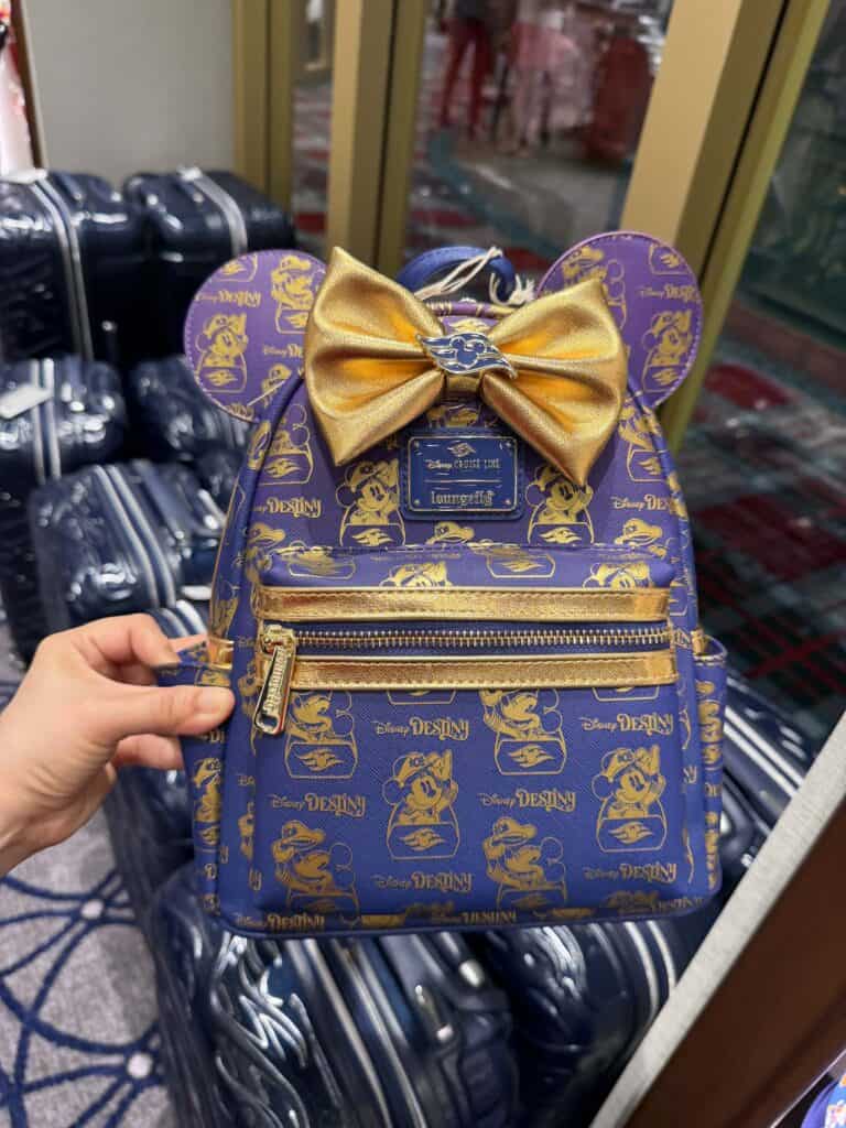 Cute Disney Loungefly mini backpack featuring Mickey Mouse print, shiny gold bow, and vibrant blue and gold accents.