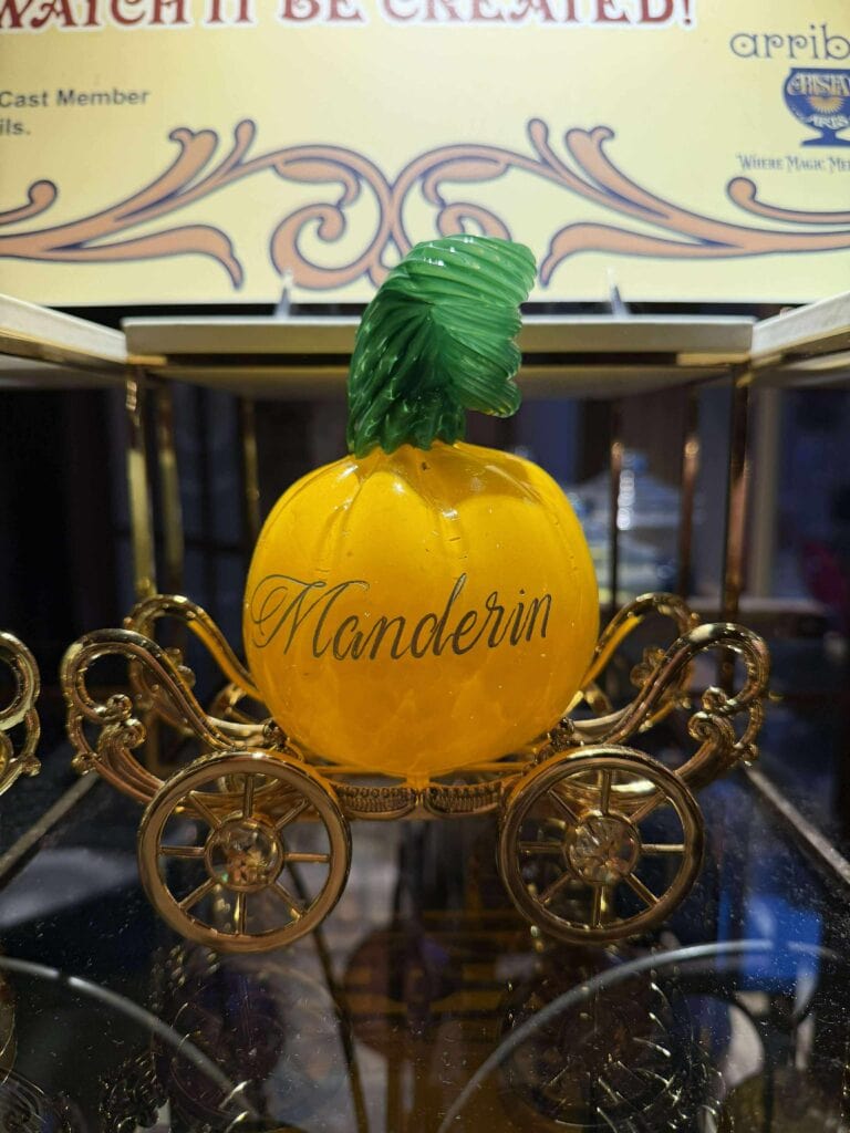 A yellow apple-shaped carriage with "Mandelin" written on it, featuring green leaves and ornate gold wheels, inspired by Disney princess themes.