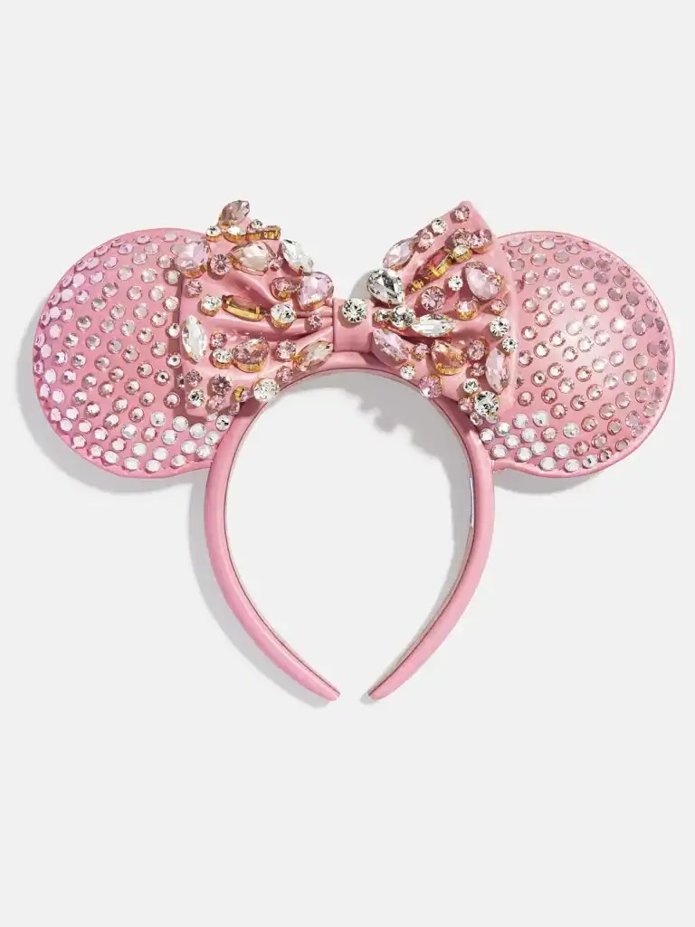 Pink Minnie Mouse ear headband decorated with rhinestones and a jeweled bow, perfect for Disney fans and fashion lovers.