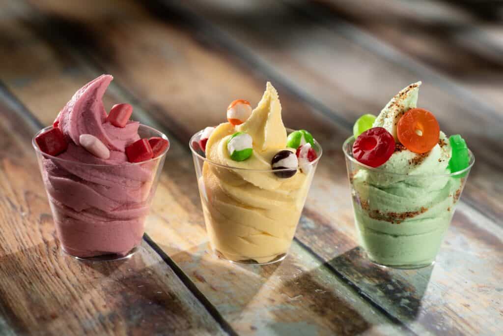 Brightly colored ice cream sundaes topped with candies in clear cups, perfect for Disney magic and fashion.