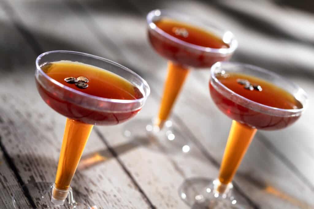 Elegant cosmopolitan drinks with orange stems and red liquid, garnished with coffee beans.
