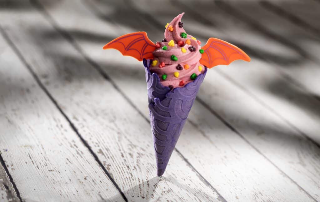 Colorful Halloween cupcake with purple wrapper and bat wing sprinkles, perfect for spooky treats.