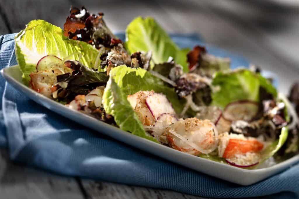 Healthy vegetable salad featuring crisp lettuce, radishes, and cherry tomatoes on a white platter.