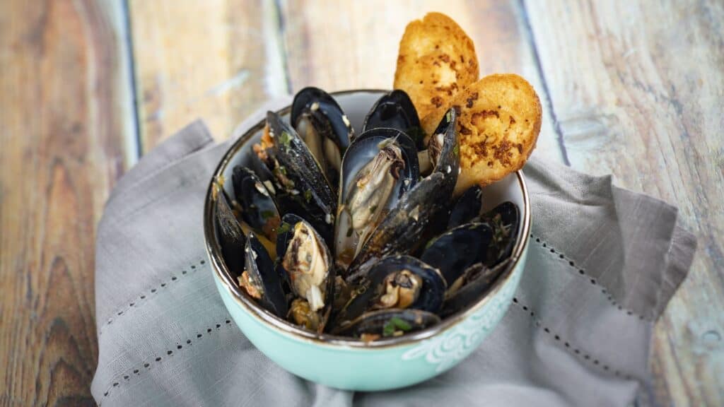 Delicious steamed mussels with herbs served with crispy potato fries, perfect for seafood lovers.