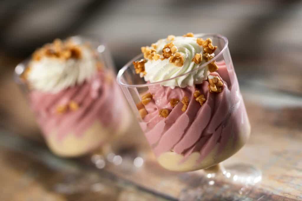 Delicious pink and white swirl parfait topped with whipped cream and crunchy nuts. Perfect for dessert or special occasions.