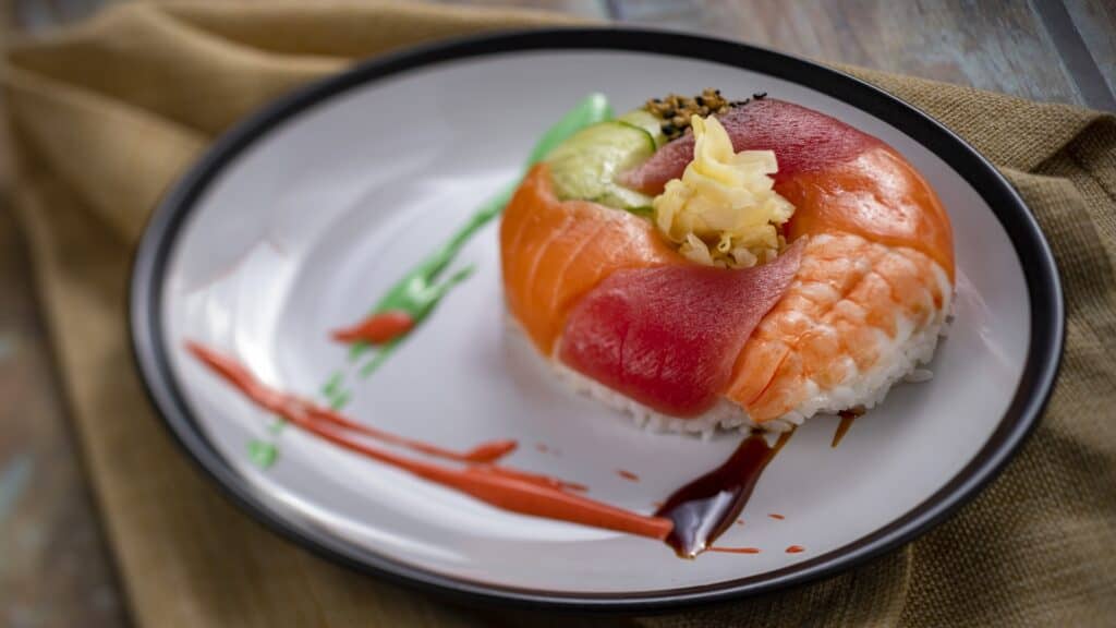 Fresh sushi with salmon, avocado, and toppings on a stylish plate.