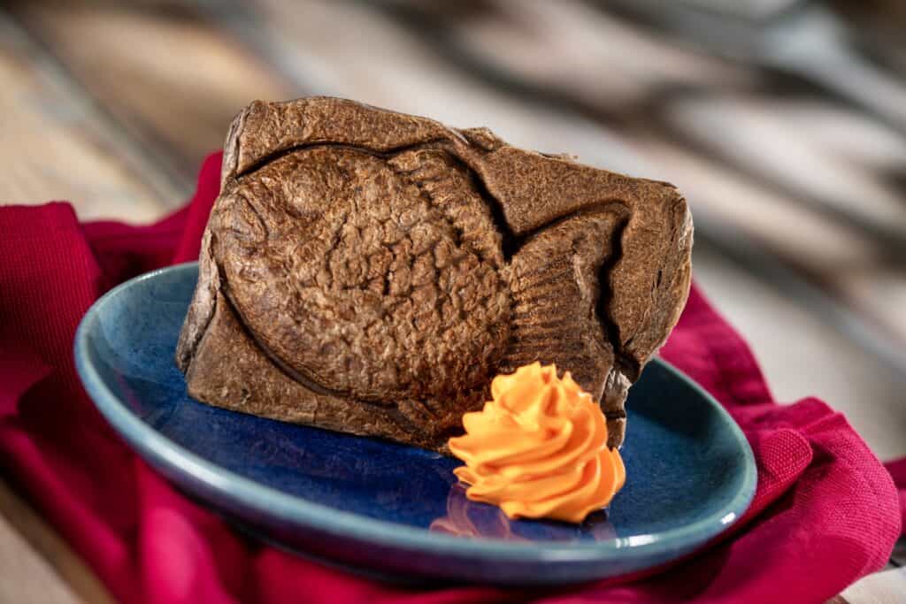 Decorative chocolate cake with a heart shape and vibrant orange frosting accent.