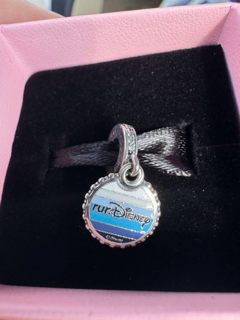Charm featuring Disney logo with blue and white striped background in a pink gift box.