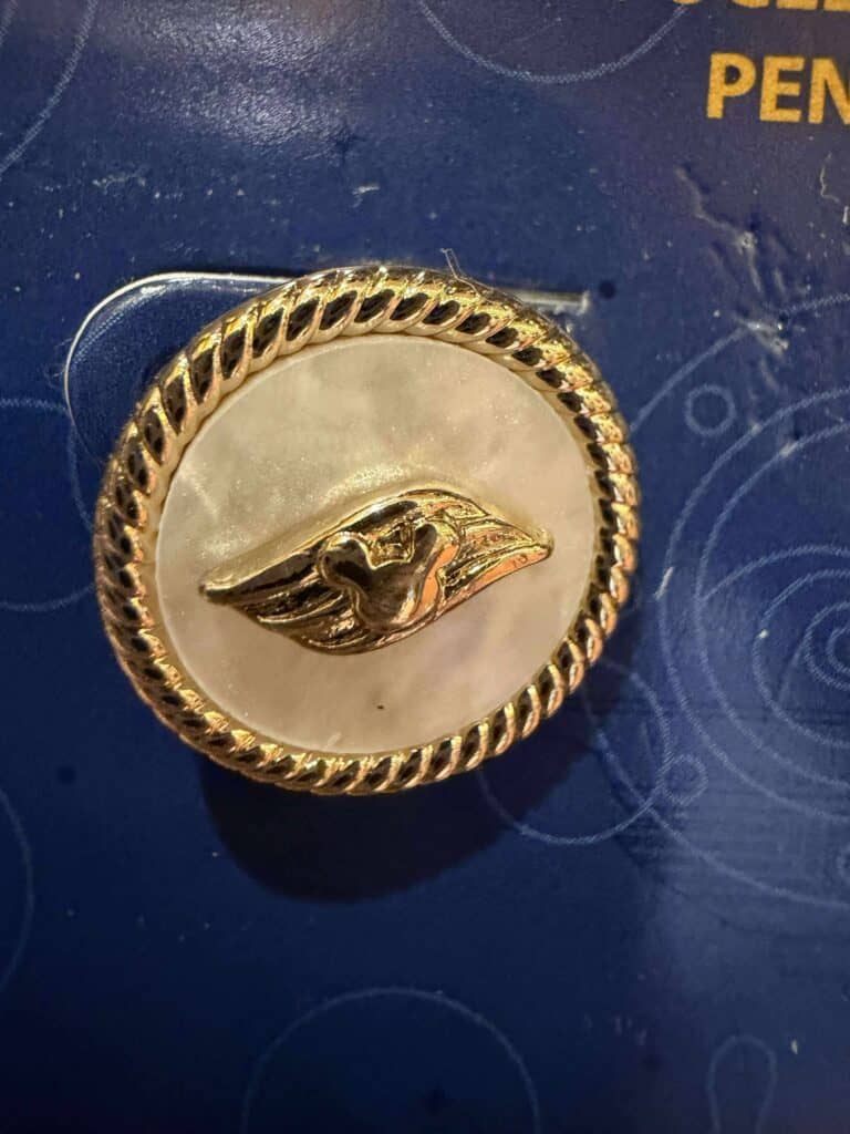 Gold-tone pin with a raised Disney face design and textured border.