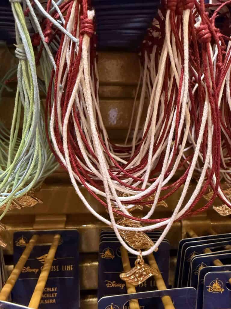 Close-up image of vibrant, Disney-themed necklaces featuring gold charms, hanging in a shop aisle.
