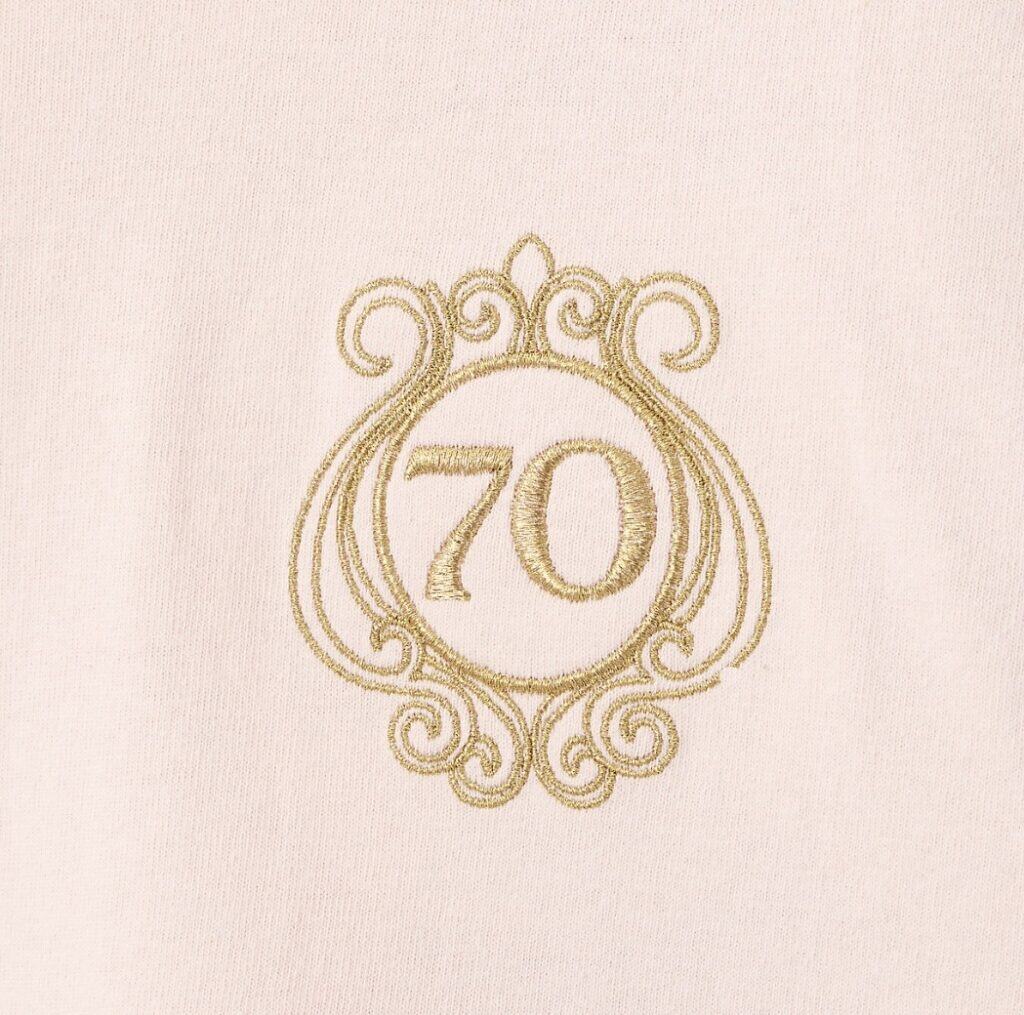 Embroidered Disney 70th anniversary on soft pink fabric, highlighting Disney celebration fashion accessories.