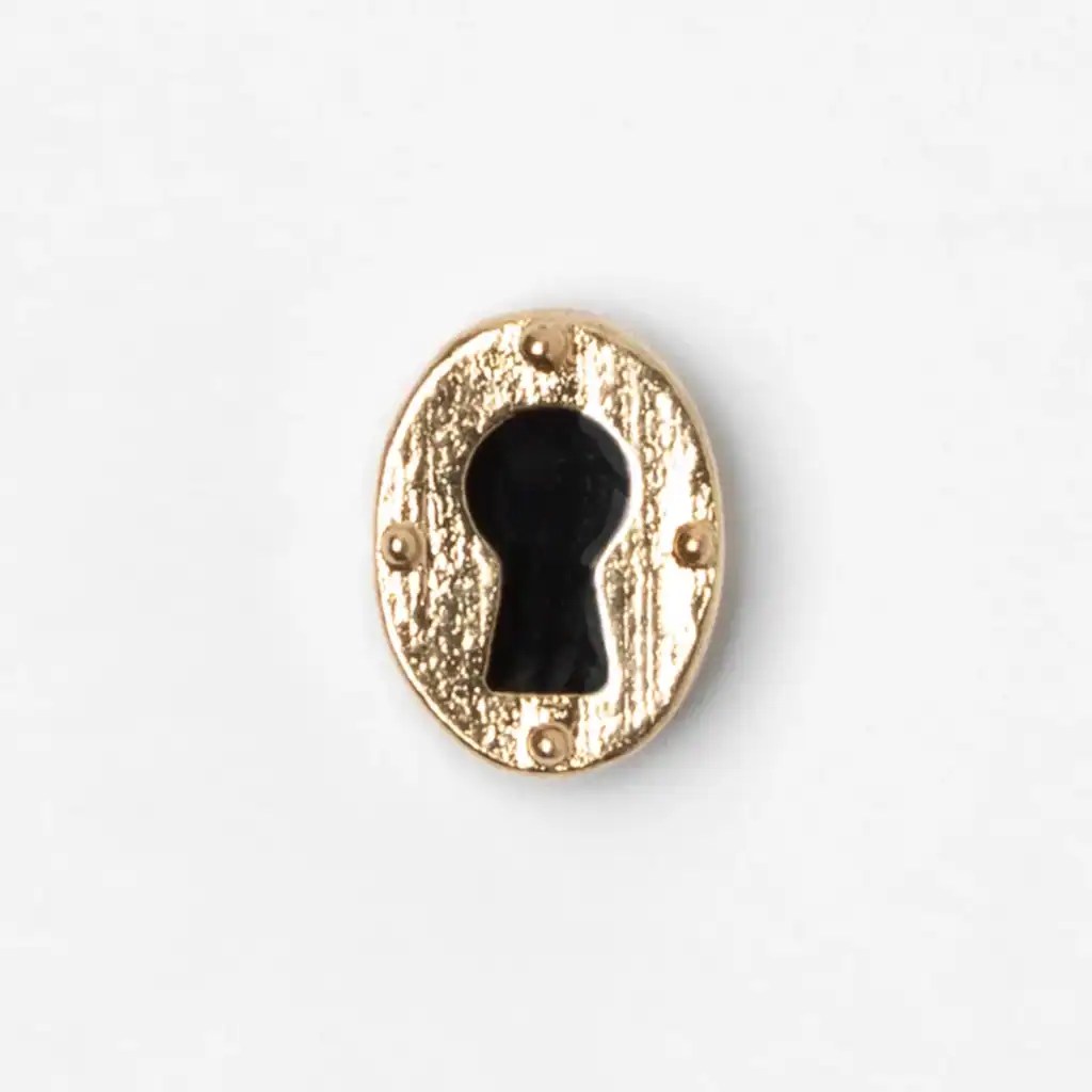 Close-up of gold-tone vintage keyhole jewelry charm on white background.