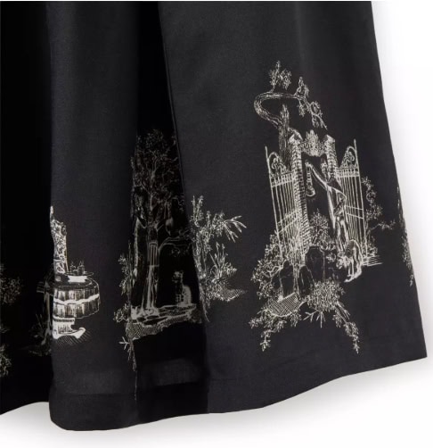 Elegant black dress featuring intricate white garden and gate print, perfect for Disney fashion lovers.