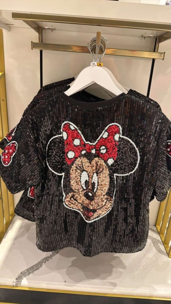 Vibrant black sequined Minnie Mouse top featuring iconic red and white polka dot bow, perfect for Disney fans.