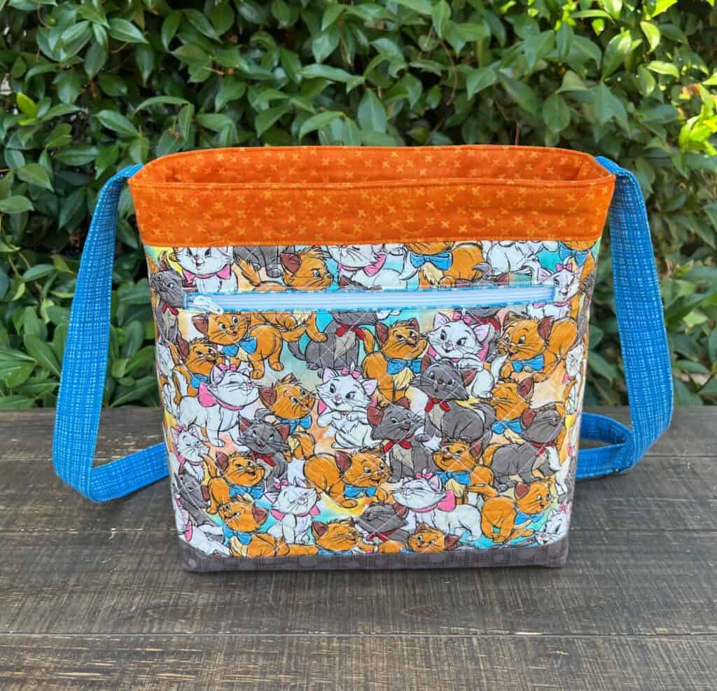 Colorful Disney cats pattern with blue straps, perfect for fans of Disney fashion and accessories.