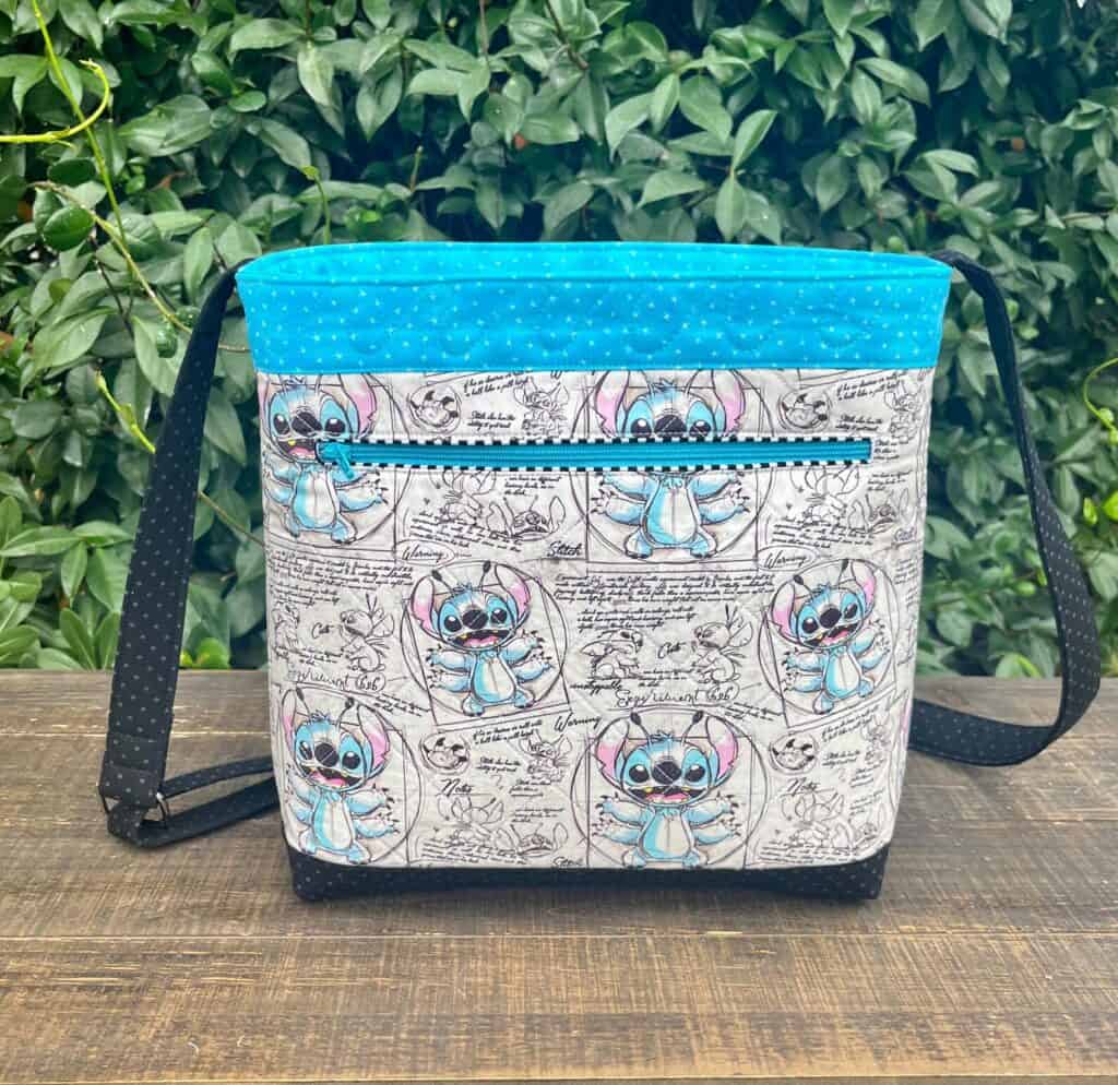 Bright blue Disney Stitch sketch art crossbody bag with zipper pocket and adjustable strap.