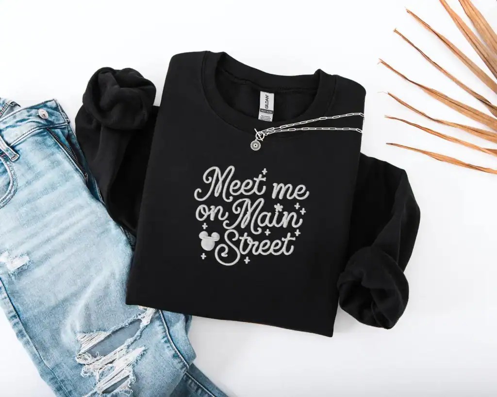 Black Disney-inspired "Meet me on Main Street" t-shirt with Mickey Mouse accents. Perfect for Disney fashion lovers and casual wear.