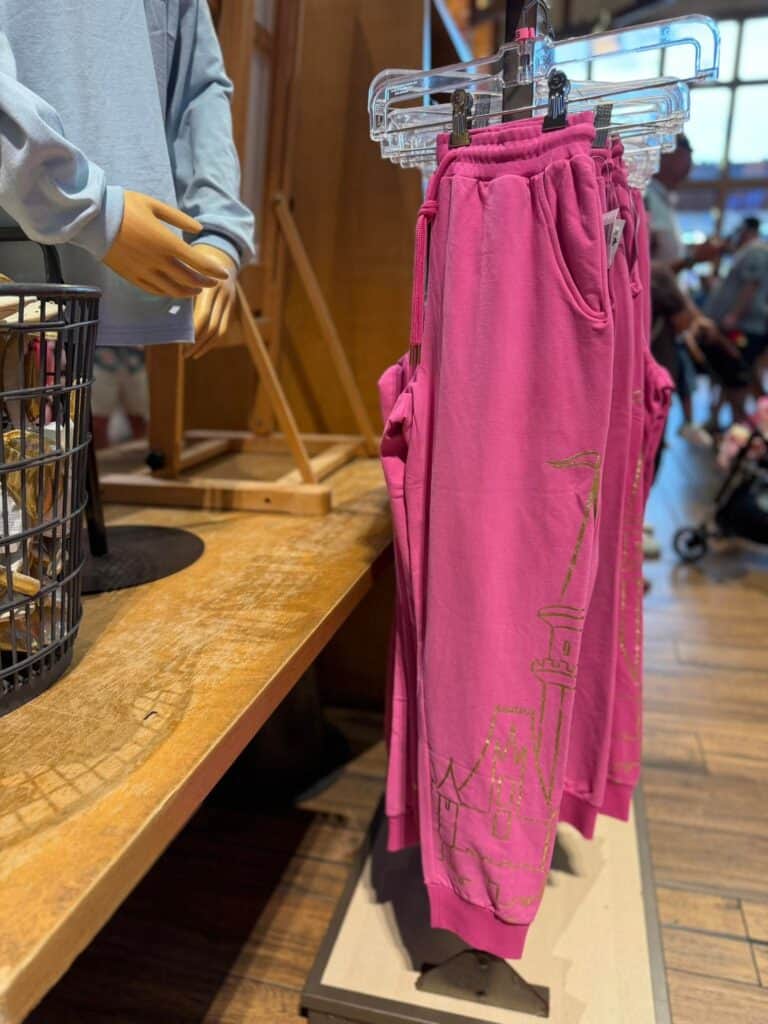 Bright pink Disney lounge pants displayed on a hanger in a retail store.