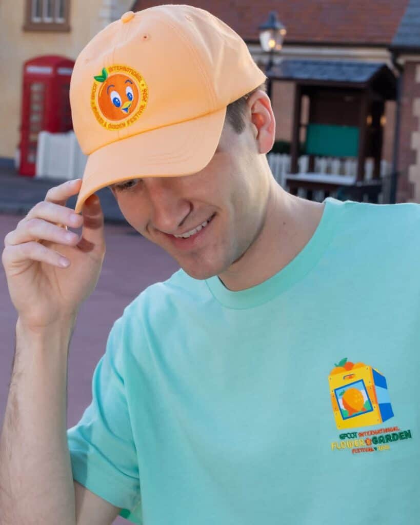 Man wearing a pastel yellow Disney-themed cap and mint green T-shirt outdoors.