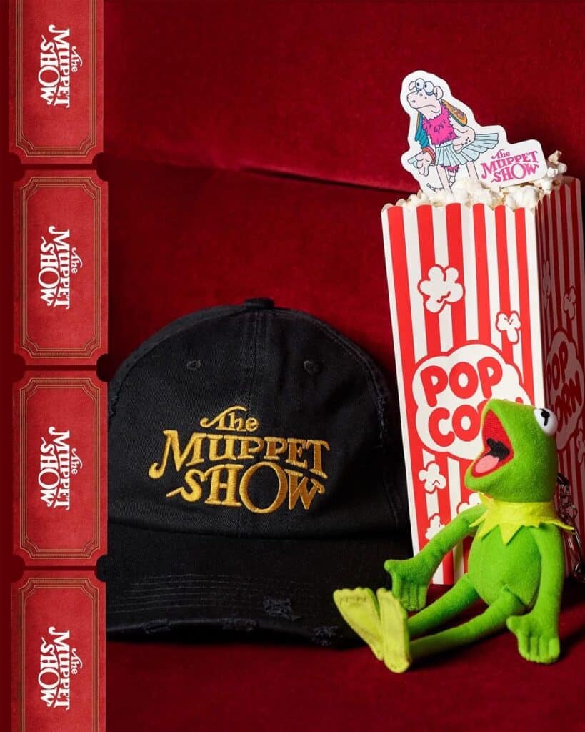 Disney Muppet Show hat, plush Kermit toy, and popcorn bucket on red background.