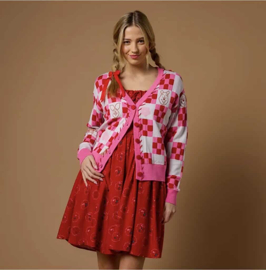 Young woman wearing a pink checkered cardigan and red dress, Disney-inspired fashion look.