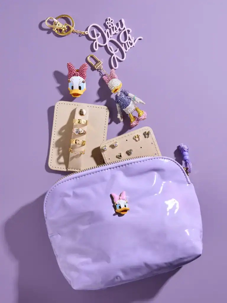 Disney-themed accessories including a bag, keychain, and jewelry on a purple background.