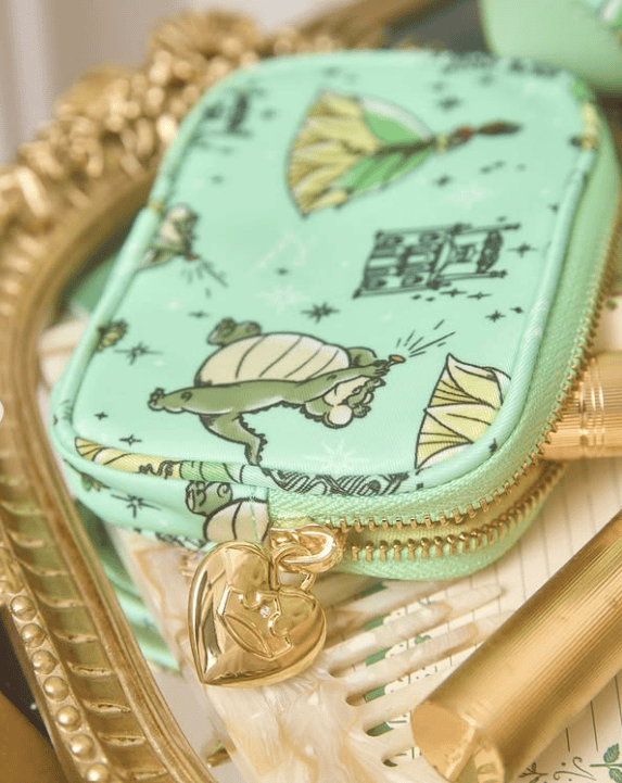 Mint green Disney-themed makeup bag with Tiana and frog illustrations, gold heart zipper pull.
