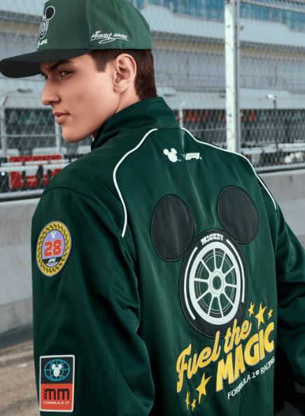 Young man wearing a green Mickey Mouse race car jacket at the racetrack.