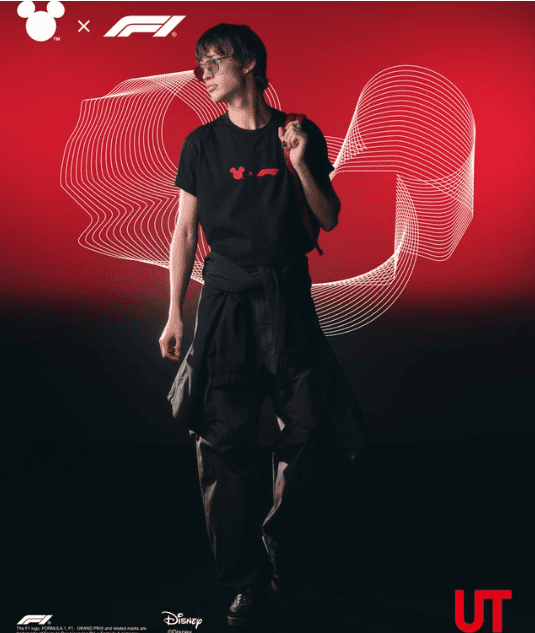 Young person wearing a black Disney F1 collaboration T-shirt with red logo, standing against a red a.