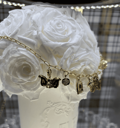 Elegant gold chain bracelet with Disney-themed charms and butterfly pendant.