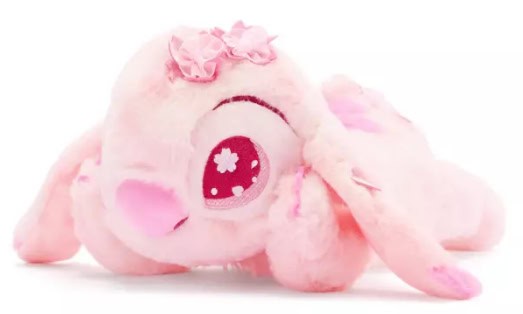 Adorable pink plush Disney elephant with floral headband and big sparkling eyes.